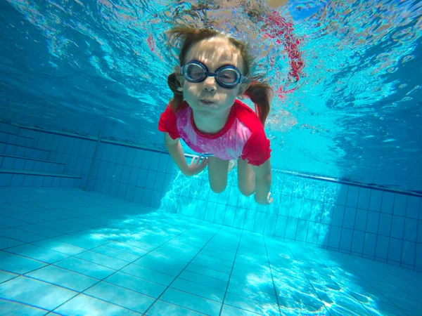 A menina no parque aquático nadando debaixo d 'água e sorrindo — Fotografia de Stock