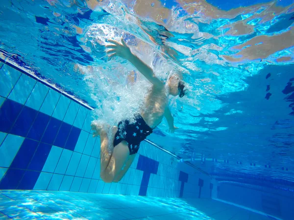 Salto do nadador da plataforma que salta uma piscina. Foto subaquática — Fotografia de Stock