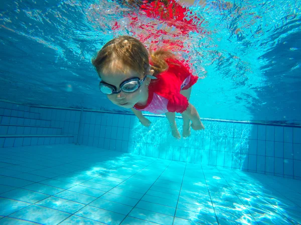 Retrato engraçado de bebê menina nadando e mergulhando na piscina azul — Fotografia de Stock