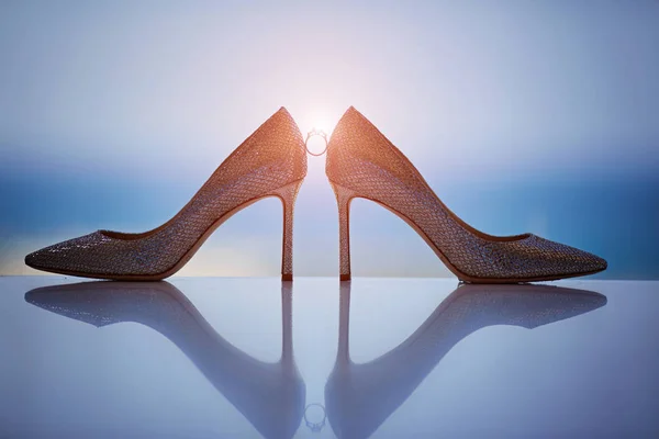 Anillos de boda de pie antes de botella de perfume entre los zapatos de mujer blanca con clase — Foto de Stock