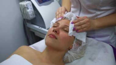 Islak peçete ile kadının yüz temizliğinde bir güzellik uzmanı görüntüsünü kapatmak.