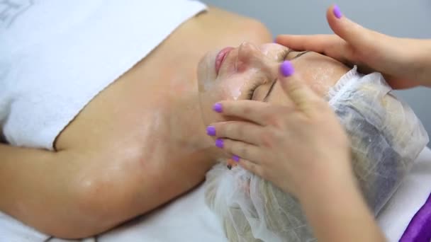 Atractiva mujer en el spa club de salud recibiendo un masaje facial. esteticista haciendo masaje de cara, cuello y hombros de hermosa joven en el salón de belleza de lujo — Vídeo de stock