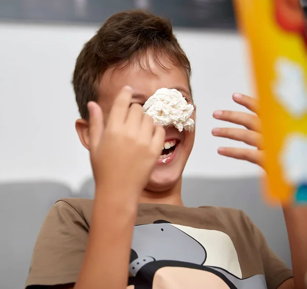 Мальчик десяти лет, играющий в забавную игру со сладким кремом, кремом в лицо — стоковое фото