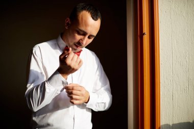 Parlak bir pencere önünde onun beyaz gömlek ayakta kadar erkek düğmeleri