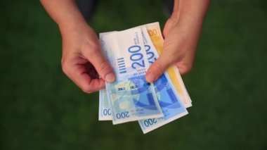 yakın çekim, yaşlı bir kadın İsrail banknotlar emekliliğinde anlatıyor.