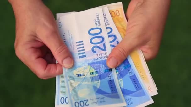 Close-up, an elderly woman recounts retirement in Israeli banknotes — Stock Video