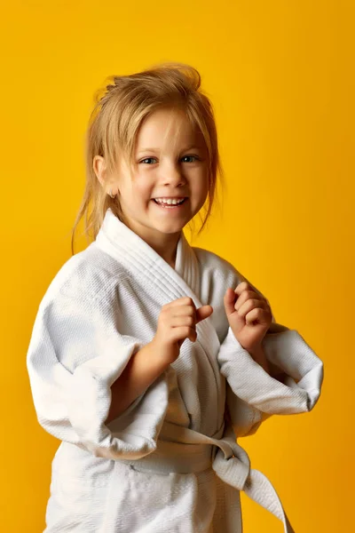 Karate kız beyaz kemer sarı bir arka plan üzerinde sağ el isabet