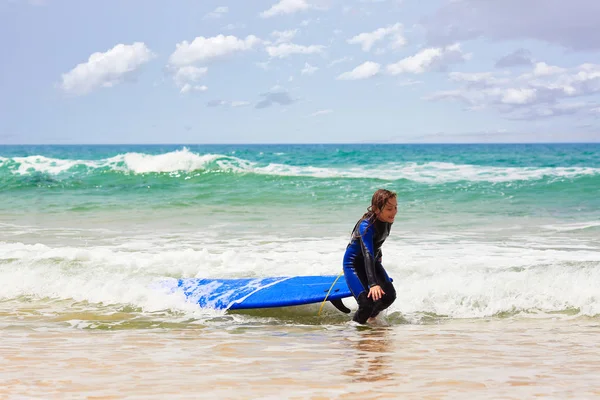 Fröhliches Mädchen zieht Surfbrett aus dem Meer — Stockfoto