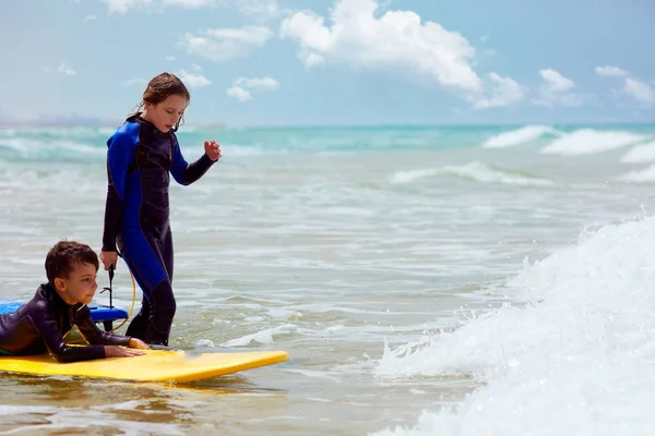 Menino e menina com pranchas de surf no mar ondulando — Fotografia de Stock