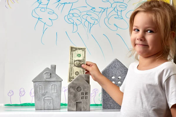 Fille avec de l'argent debout près des maisons de jouets — Photo