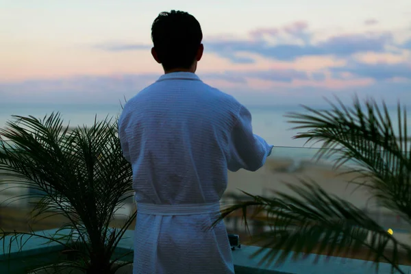guy in a hotel bathrobe enjoying the sea view sunset