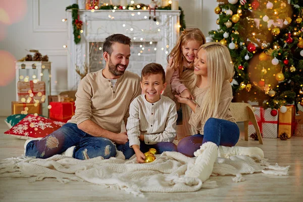 Família feliz com caixas de presente sentadas perto da árvore de Natal na véspera de Natal — Fotografia de Stock