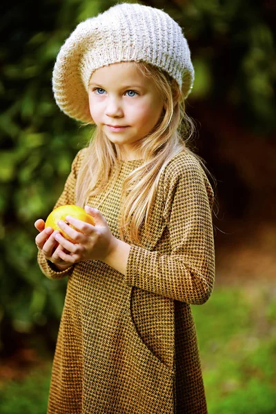 Fille aux yeux bleus dans une robe avec une orange dans ses mains — Photo