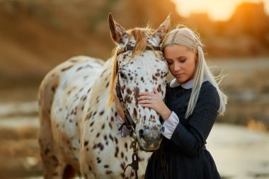 Sensual woman embracing horse in sunlight clipart