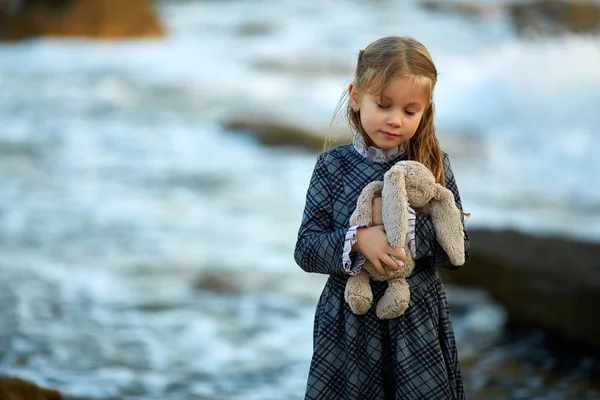 Flicka i klänning holding kanin leksak i naturen — Stockfoto