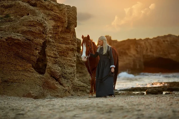 Kvinna med häst på steniga havsstrand — Stockfoto
