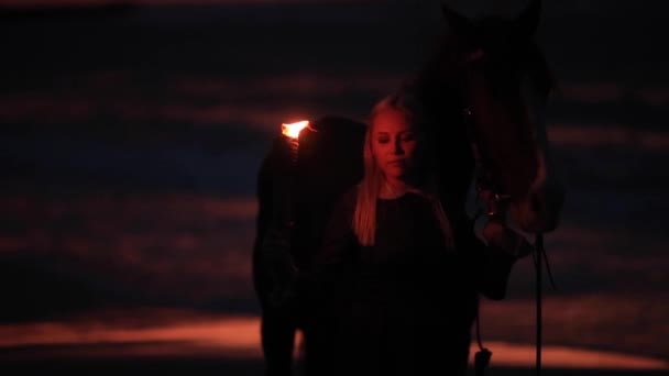 Dziewczyna z ogniem spacery z koniem brzegiem morza w nocy — Wideo stockowe
