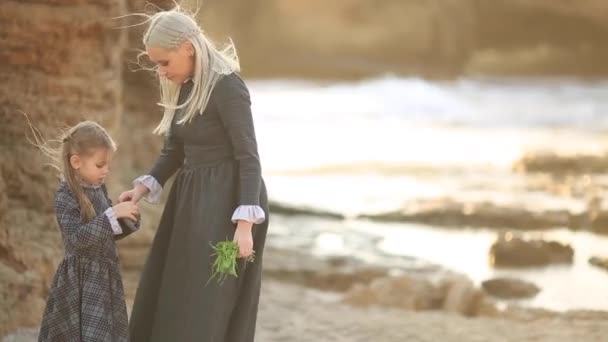 Mladá matka a dcera hrát a chodit na kamenité pláži při západu slunce — Stock video