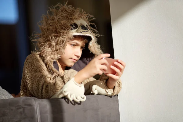 Pojken i lättja pyjamas spelar mobiltelefon — Stockfoto