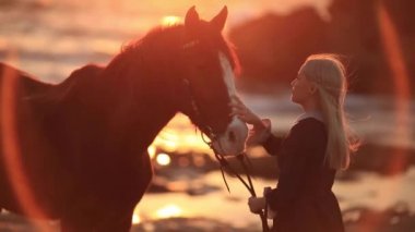 Woman with horse on rocky seashore. Love and friendship concept.