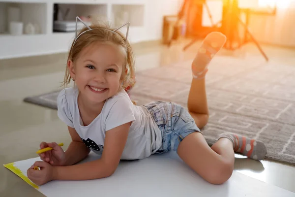 Feliz niña. Foto mirar lado chicas creativas que yacen cerca de libros y juguetes, dibujar — Foto de Stock