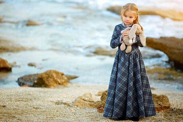 Chica en vestido celebración de juguete de conejo en la naturaleza —  Fotos de Stock