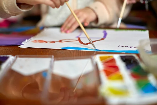 Детский рисунок и масса инструментов для рисования на деревянном фоне — стоковое фото