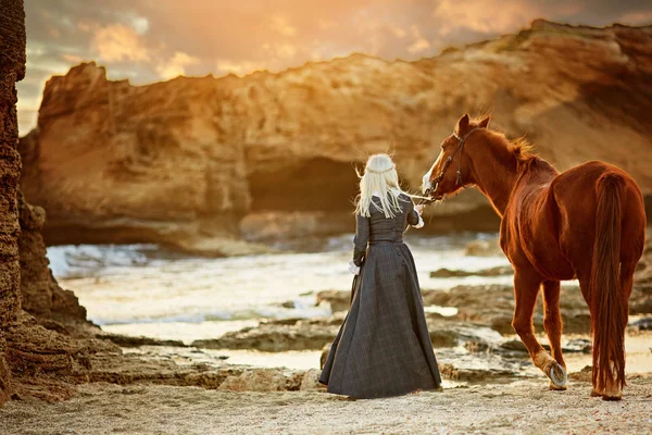 Ung blond tjej smeka en brun häst — Stockfoto