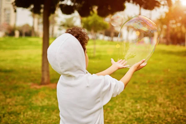 Анонімний дитина грає з мильною бульбашкою в сонячний день — стокове фото