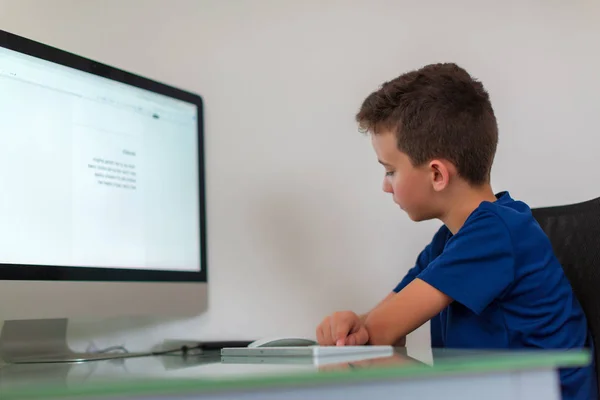 Okul çocuğu evde kişisel bilgisayar üzerinde çalışıyor. Öğrenci modern PC kullanarak ödev yapıyor — Stok fotoğraf