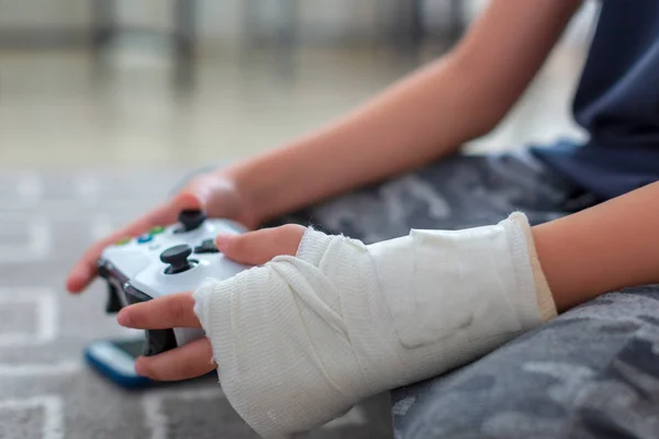 Kind met gebroken arm met behulp van video game controller — Stockfoto