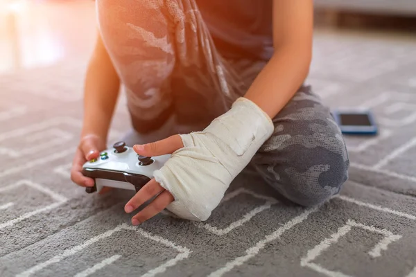 Jongen met blessure thuis. Yonge video gamers handen met behulp van een gamepad — Stockfoto