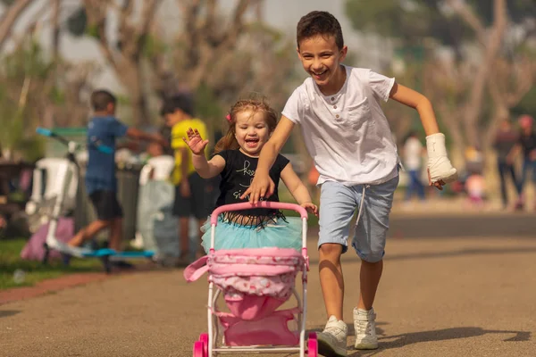 Хлопчик і дівчинка грають у гру дітей, які грають у колясці в парку. Дитяча дружба — стокове фото