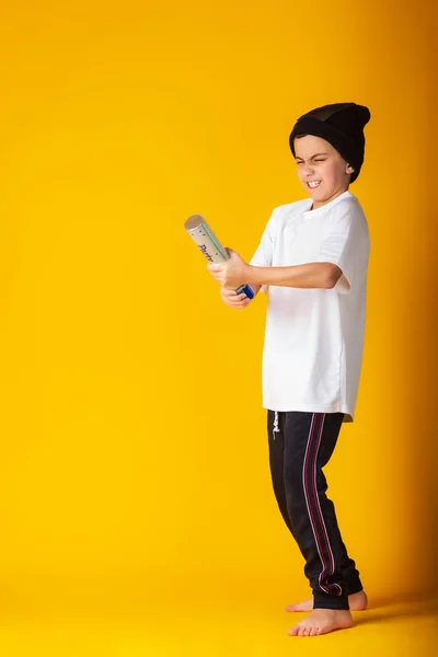 Petit garçon ludique en t-shirt blanc et chapeau explosant partie popper debout sur fond jaune — Photo