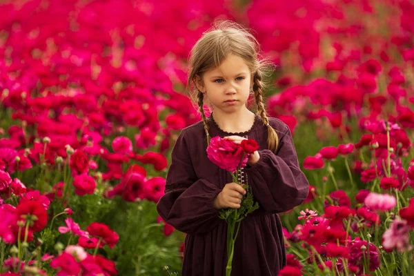 Meisje in een kersen jurk en Pigtails verzamelt helder roze bloemen — Stockfoto