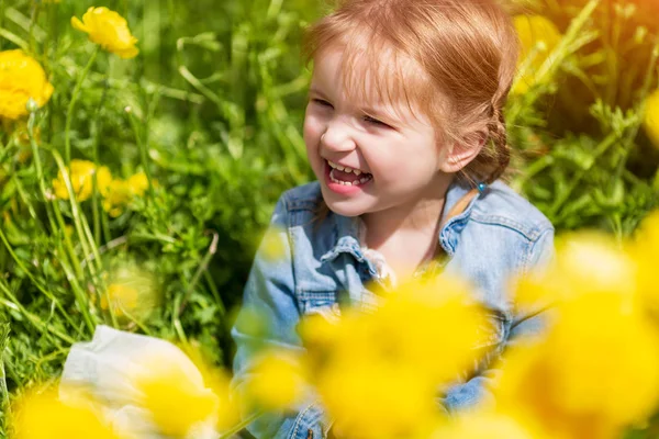 Liten Blond bebis mellan gula blommor leende och tittar bort — Stockfoto