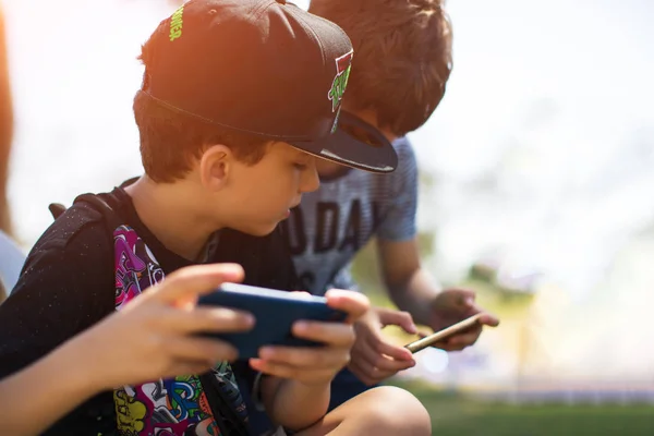 Petit garçon enfant jouer à des jeux mobiles sur smartphone dans le parc — Photo