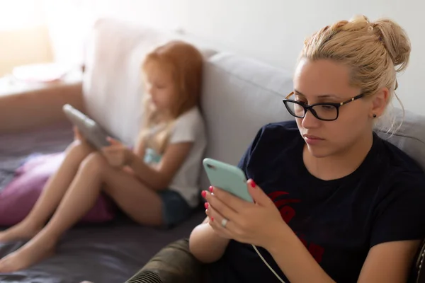 Mujer y niño se ve ocupado con gadgets — Foto de Stock