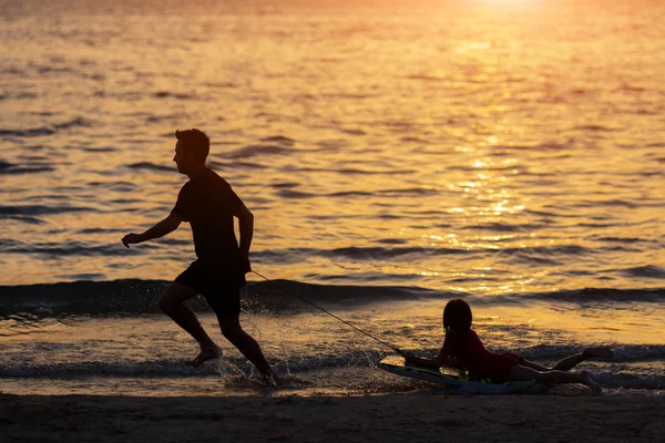 Silhueta Pai e criança brincando na praia na hora do pôr do sol. Pai e criança se divertindo ao ar livre — Fotografia de Stock