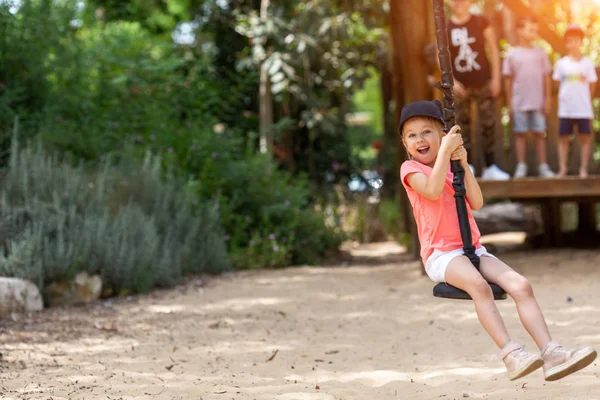 Pequeña chica escandinava rubia valiente montando en un columpio bungee en el patio del parque en el día soleado de verano — Foto de Stock