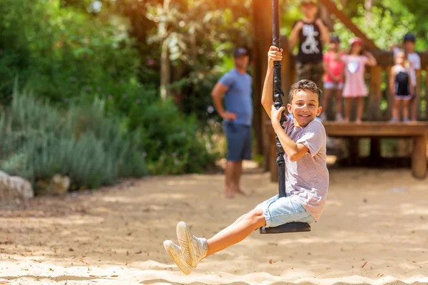Усміхнений хлопчик катається на бунгало в парку на дитячому майданчику — стокове фото
