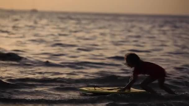 Силуети дітей, які грають з дошками на морі повільний рух — стокове відео