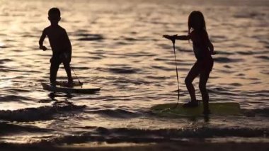 Gün batımında sahilde oynayan mutlu çocuklar. Yaz tatili konsepti, dost aile