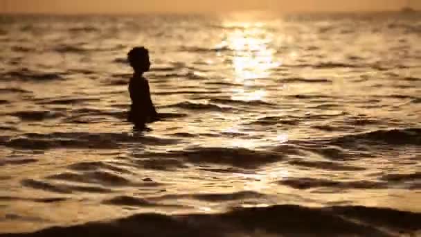 Chłopiec zabawy w morzu o zachodzie słońca, poszukiwanie fizycznej i duchowej harmonii na planecie Ziemia. — Wideo stockowe