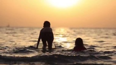 Güneş parlamasında deniz suyunda oynayan çocuklar, denizde oynayan tanınmayan çocuklar silueti