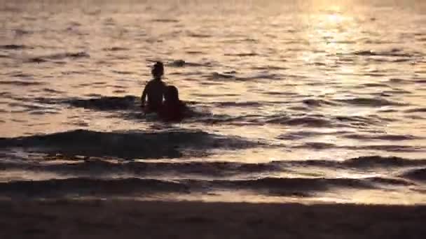 Dvě děti, které hrají ve vodě při západu slunce — Stock video