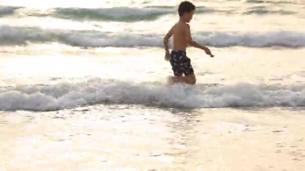 Menino pequeno feliz executar jogar com ondas na praia — Vídeo de Stock