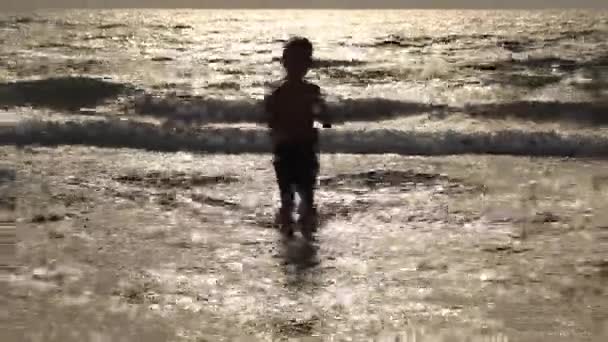 Junge spielt in den Wellen am Strand im Sommer Sonnenuntergang, Kind beobachtet Meereswellen und hat Spaß