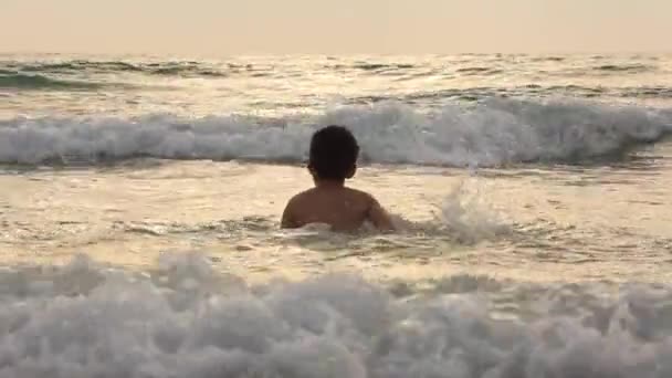 Petit garçon jouant et éclaboussant la vague de l'océan — Video