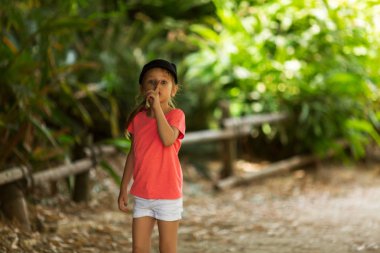 Açık havada yürürken sessiz işareti gösteren kız